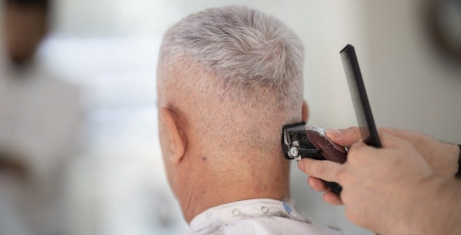 homme aux cheveux qui blancs en train de se faire couper les cheveux