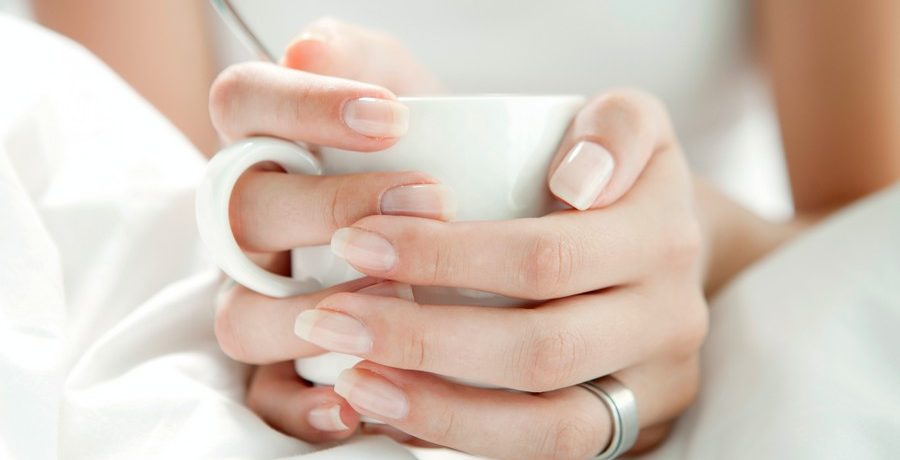 mains d'une femme qui tiennent une tasse blanche