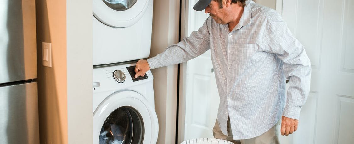 Un homme devant une machine à laver.