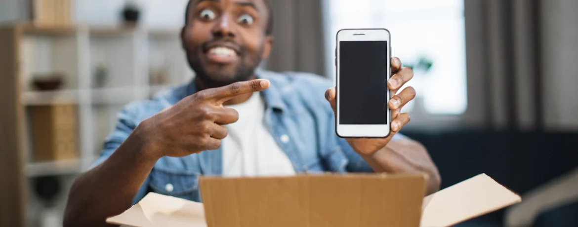 Un homme qui montre un smartphone qu'il vient de sortit d'un carton