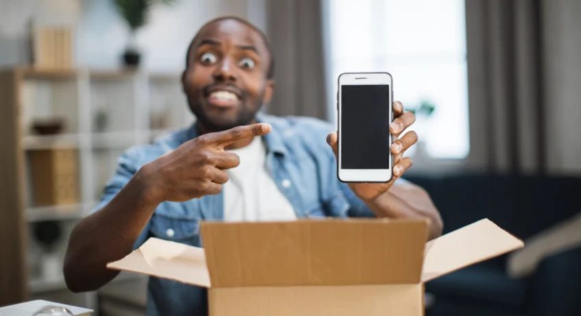 Un homme qui montre un smartphone qu'il vient de sortit d'un carton