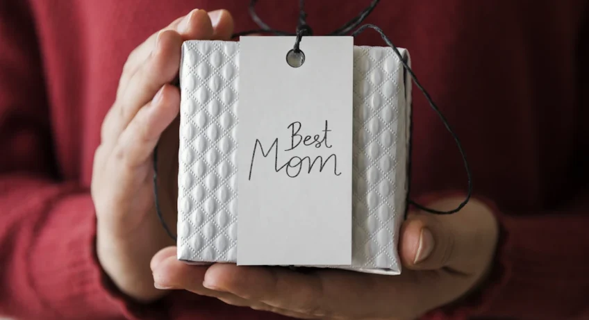 Une personne qui tient un paquet cadeau avec une étiquette best mom